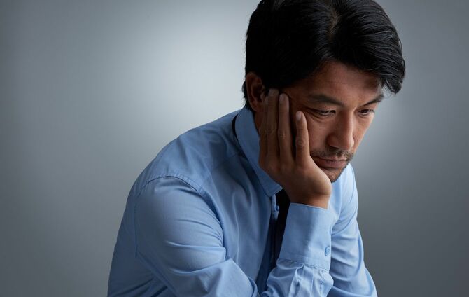 頬杖をついて悩ましげな表情をしている男性