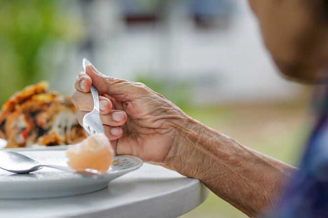 高齢の女性は裏庭で朝食を食べる