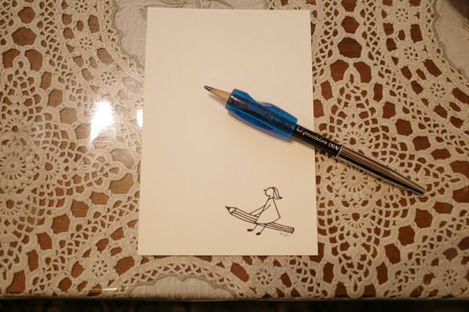 春日さんが愛用するグリップをはめた鉛筆。お孫さんのイラストが入ったはがきとともに