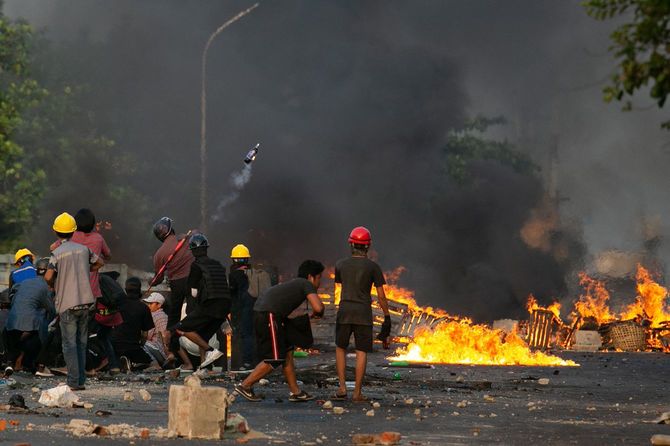 2021年3月16日、ミャンマー・ヤンゴンで行われた軍事クーデターへの抗議デモが弾圧されている。デモ参加者がガソリン爆弾を投げ、他のデモ参加者は手作りの盾の後ろに隠れて警察と対峙している。