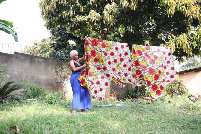 アフリカンプリントが施された布を天日干しする女性