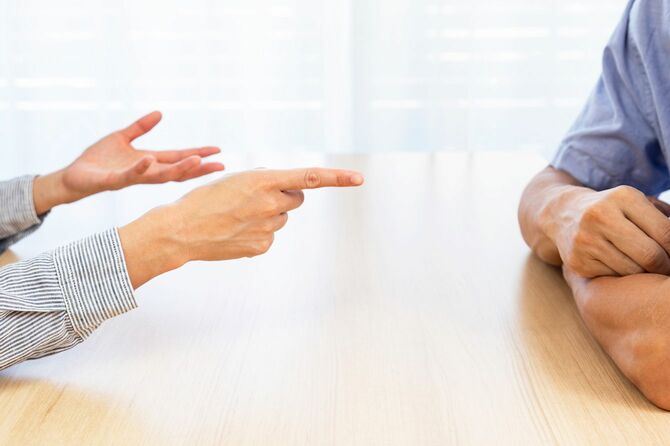 机を挟んで座り、口論している男女