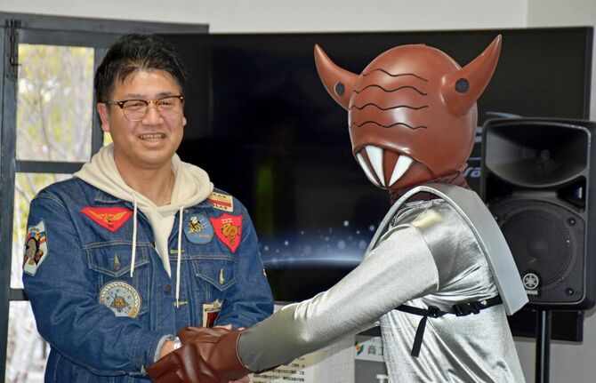 「甲府星人」と握手する「甲府UFO事件」の目撃者・山畠克博さん＝2024年2月、甲府市