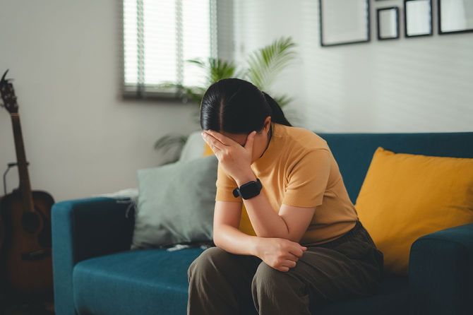 ソファに座って頭を抱えている女性