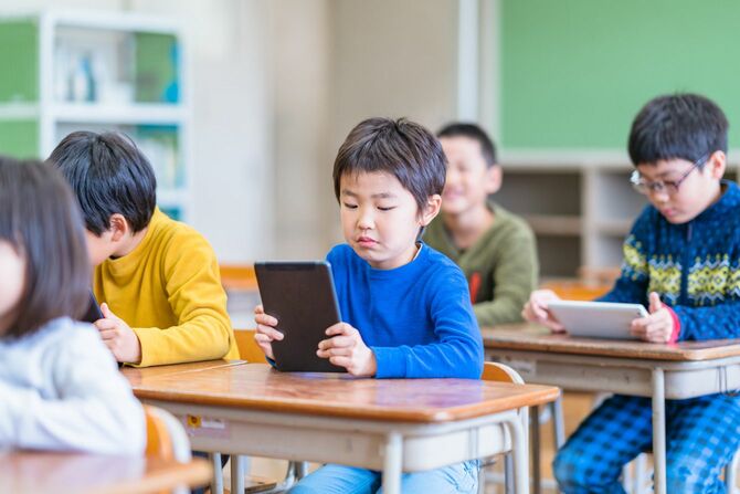 教室でデジタルタブレットを使用する学校の子供たち