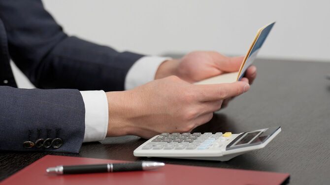 通帳を見て計算するビジネスマン