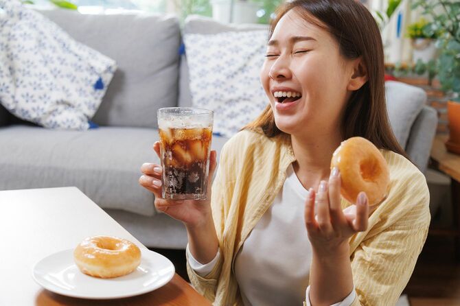 ドーナツとコーラを手に笑顔の女性