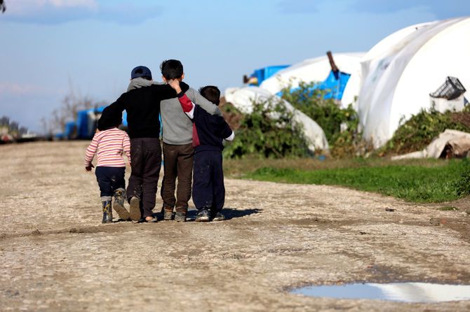 難民キャンプで肩を寄せ合い歩く子供たち