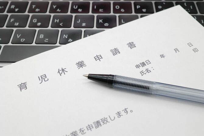 ノートパソコンの上に、育児休業申請書とペン