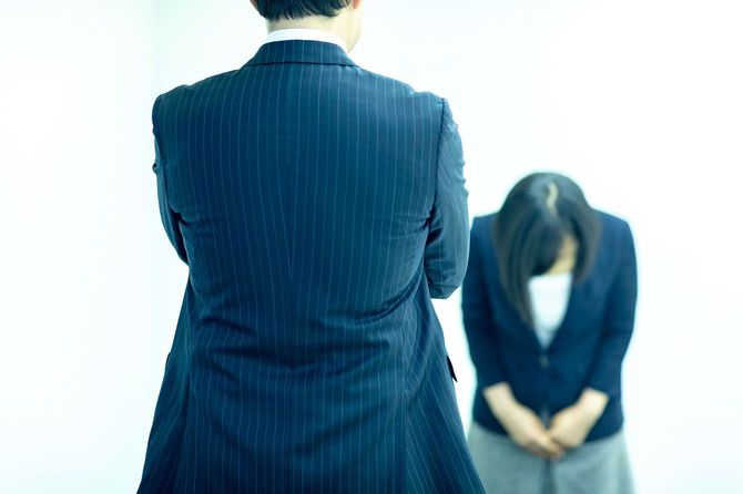 腕を組んでいる男性に、深くお辞儀をする女性