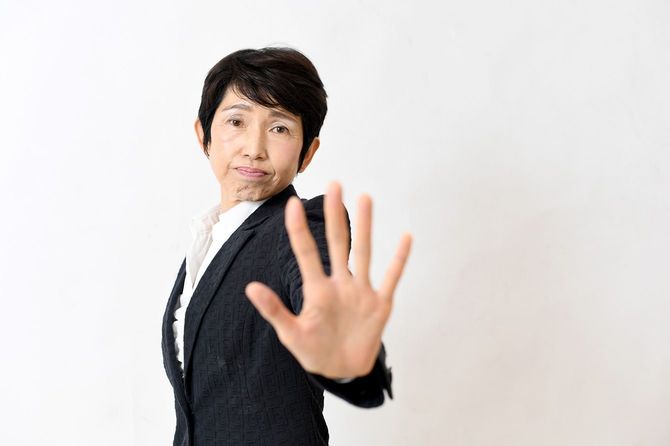 こちらに手のひらを向けるスーツを着た女性