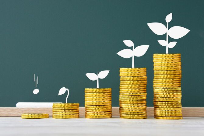 黒板の前に右肩上がりで増えているコインと黒板には成長していく芽のイラスト