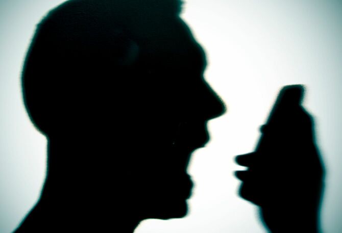 電話に向かって怒鳴る男性のシルエット