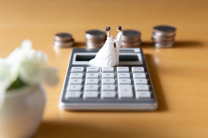 電卓の上に置かれた、結婚式中のカップルのミニチュア人形