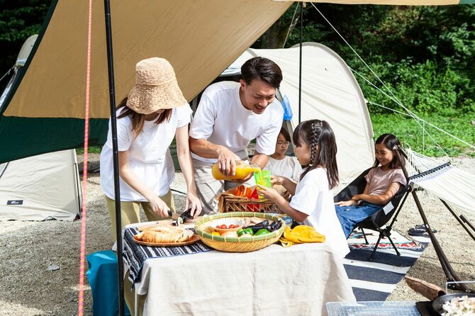 キャンプ場でバーベキューの準備をする家族