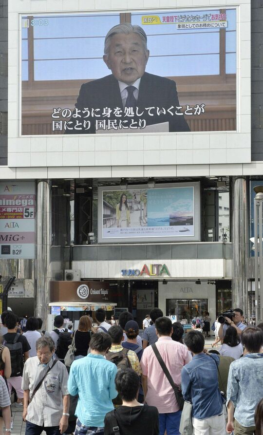 2016年8月、上皇さまのビデオメッセージを映す大型モニターを見る人たち＝東京・新宿