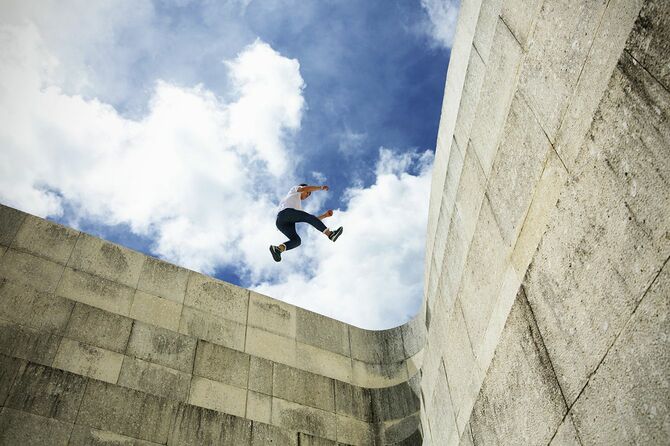 若い男はコンクリートの壁にジャンプ