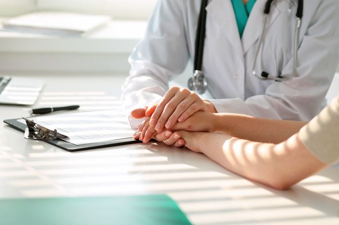 患者の手をとる医師