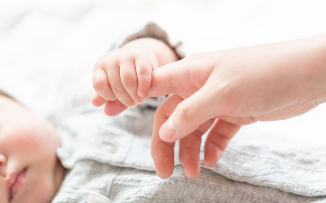 母親の指を握る赤ちゃん