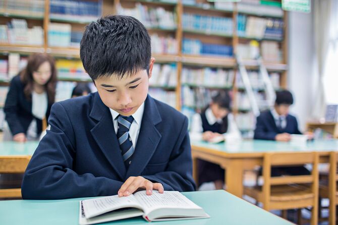 学校の図書館で本を読む日本人の男の子