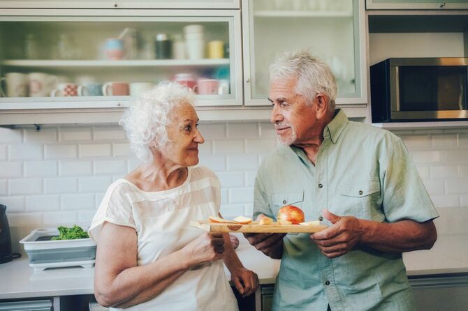 キッチンでリンゴを食べる老夫婦