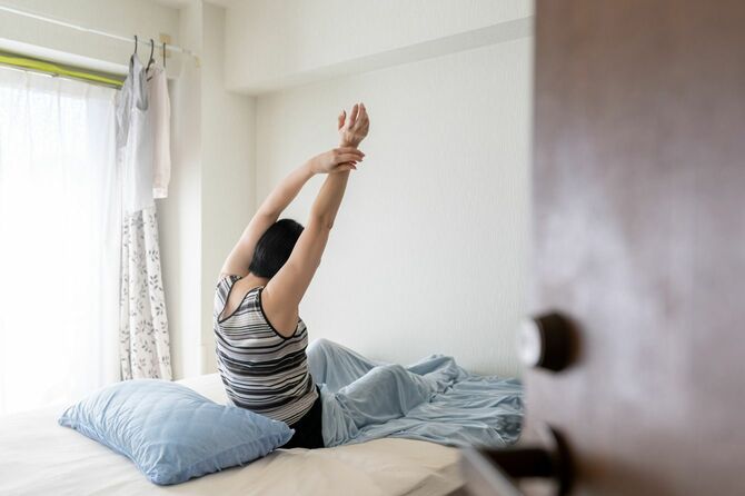 朝起きて、ベッドで伸びをする女性