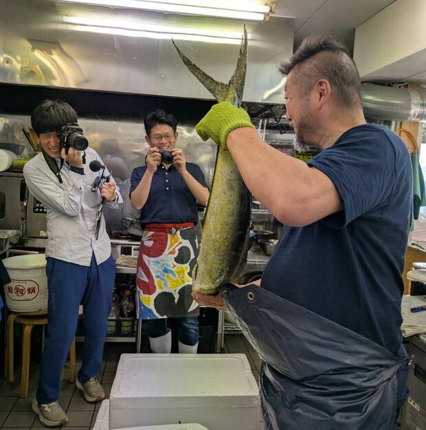 上田さんのいるサカナヤマルカマには魚好きな客だけでなくメディアも集まって来る。右から、シイラを見せてくれる上田さん、筆者、水産新聞記者の市川さん（サカナヤマルカマ撮影）
