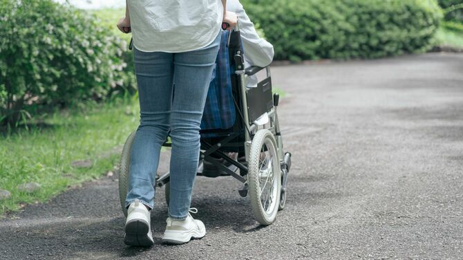 公園で老人の車椅子を押す人