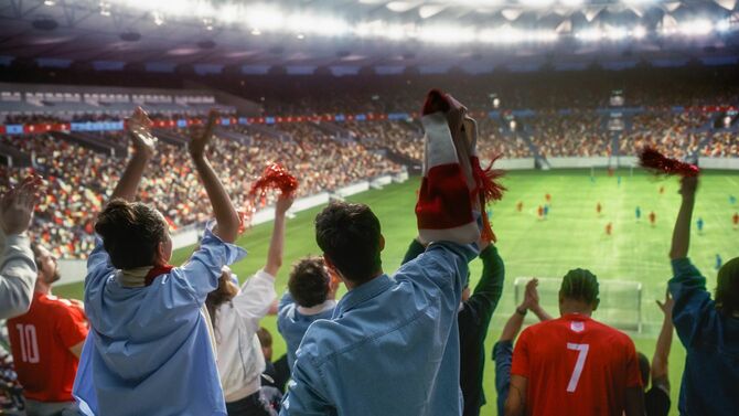 サッカーの試合をスタジアムで観戦する人々