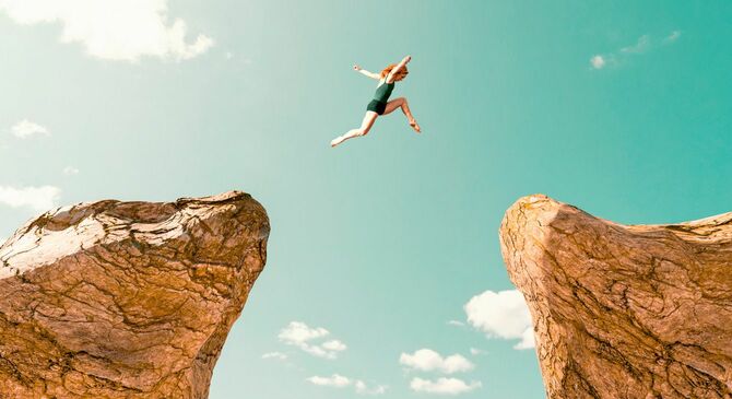 岩から岩へ危険なジャンプをする女性