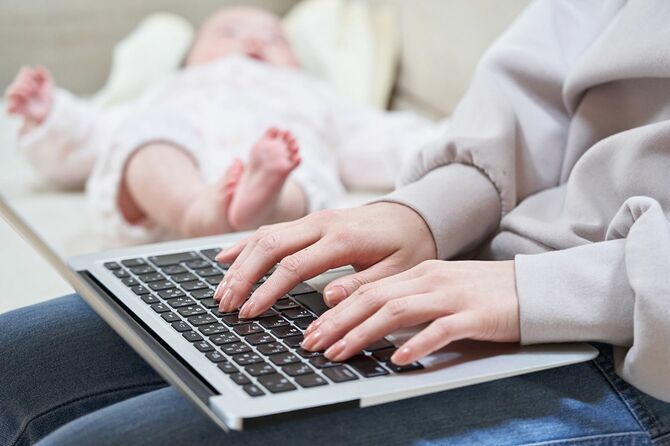 コンピュータ上で子育てを見上げるアジアのお母さん