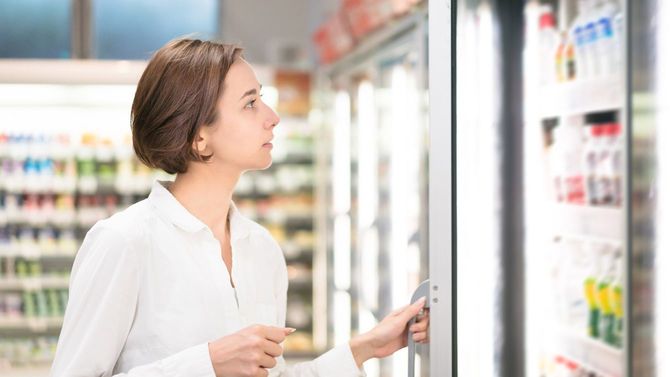 スーパーで冷蔵庫の扉を開ける女性