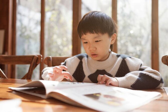 太陽の光の部屋で読書をする小さな男の子