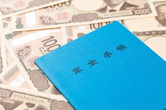 敷き詰めたお札の上の年金手帳