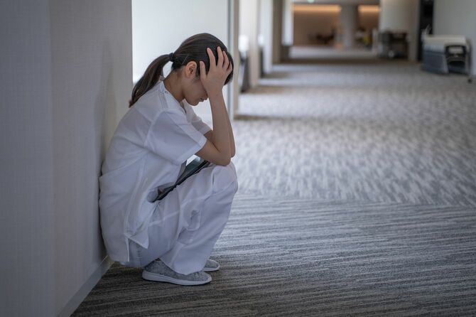 廊下にうずくまる看護師