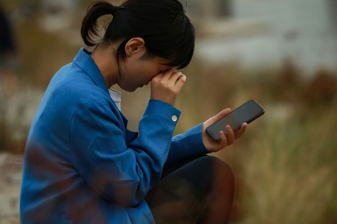 スマートフォンを手に泣いている女性