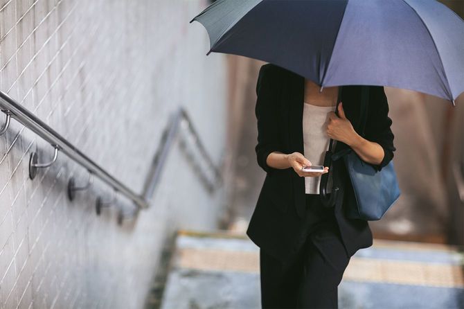傘を持って地下鉄の階段を歩いている女性