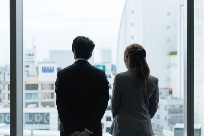 並んでオフィスの窓から外を見ている男女