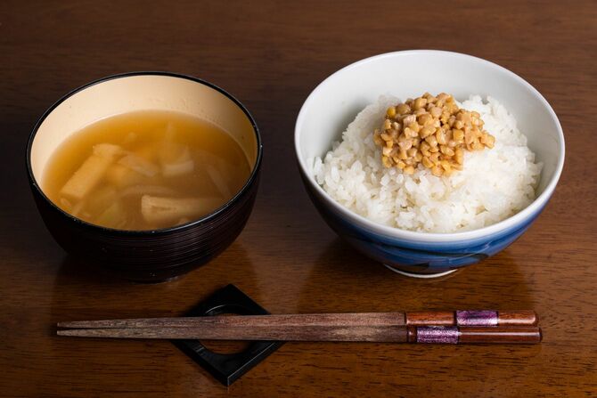 納豆をのせたご飯の入った茶碗と味噌汁の入った器とお箸