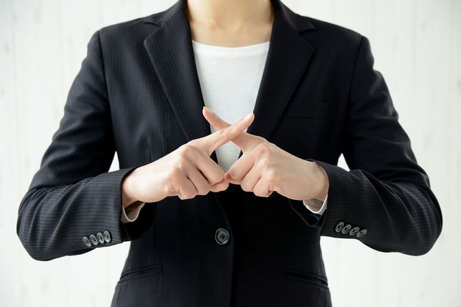 手でバツを作る女性