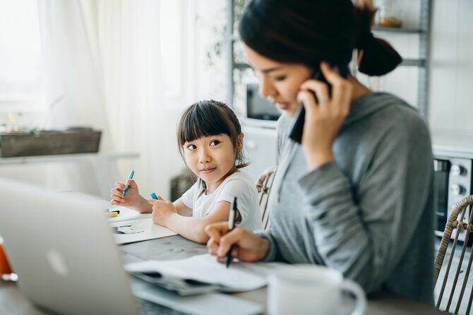 ラップトップで自宅で仕事をし、小さな娘が家から勉強している間に電話で話しています。