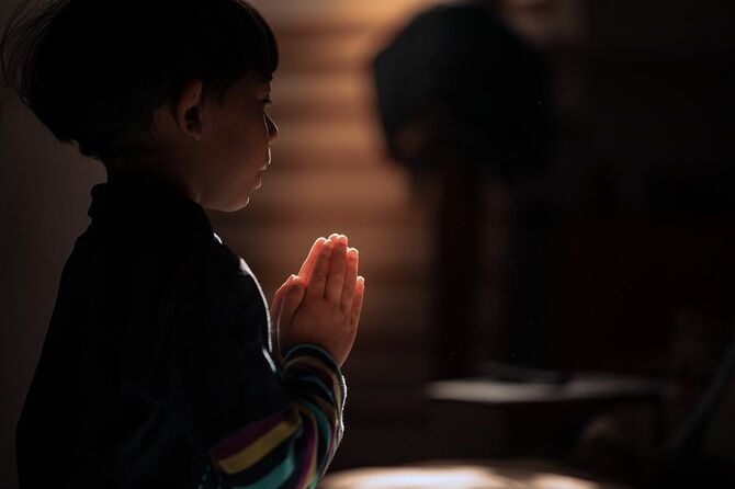 結合を照らす暖かい霊的な光の中で祈る子供