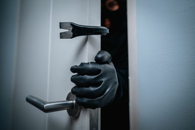 黒川の手袋をはめ、バールのようなものでドアをこじ開けている犯罪者