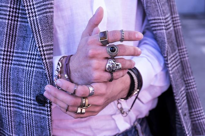 多数のシルバーリングやブレスレットを重ね付けした男性の手元