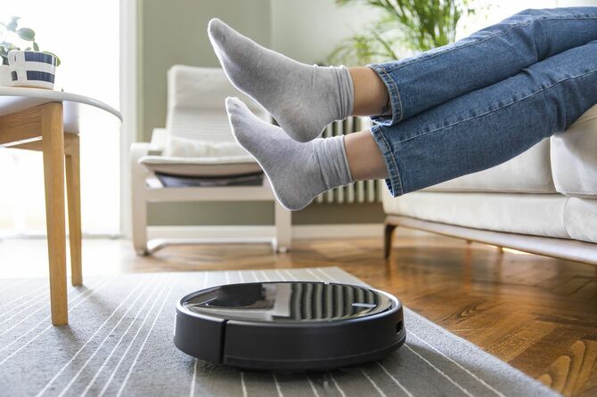ロボット掃除機を通すために床から足を持ち上げている人