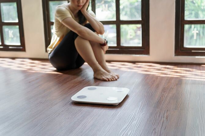 体重計を見て悩む女性