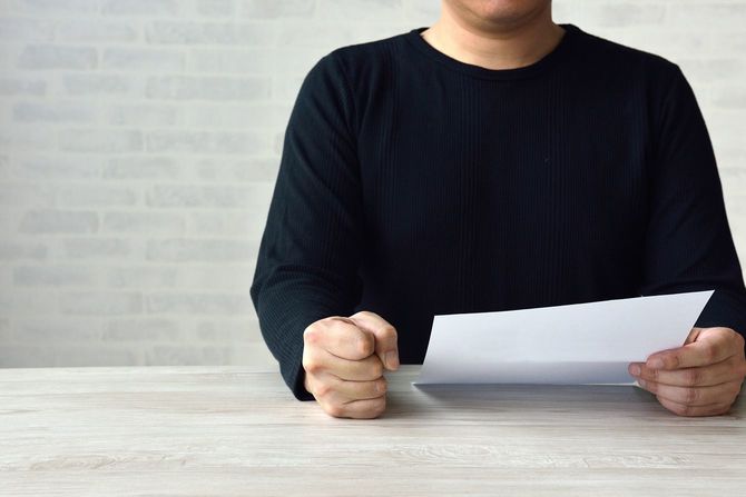 書類を見ながら怒る男性