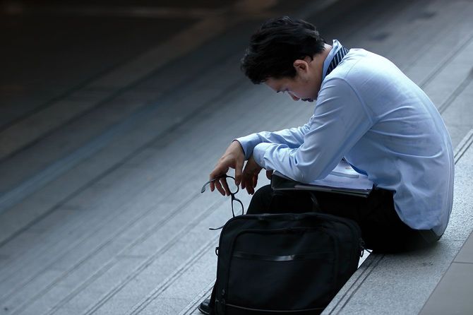 落ち込んで外の階段に座っている男性