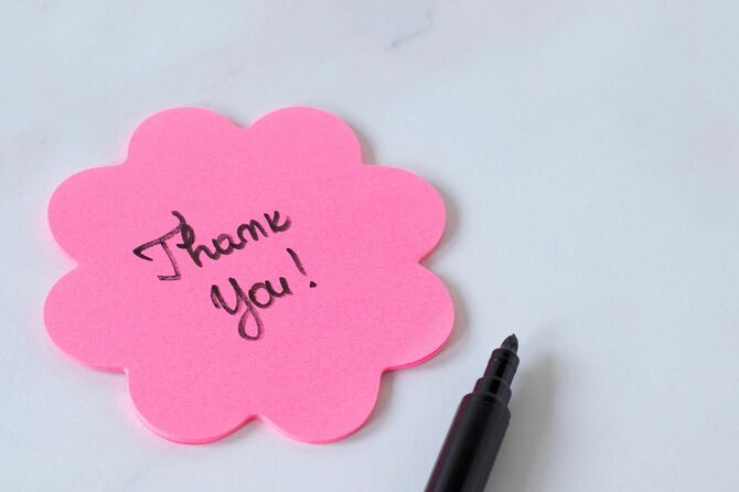 お礼の花の形をしたピンクの付箋紙に手書きのありがとうテキスト