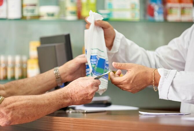 薬局で薬を購入する高齢男性